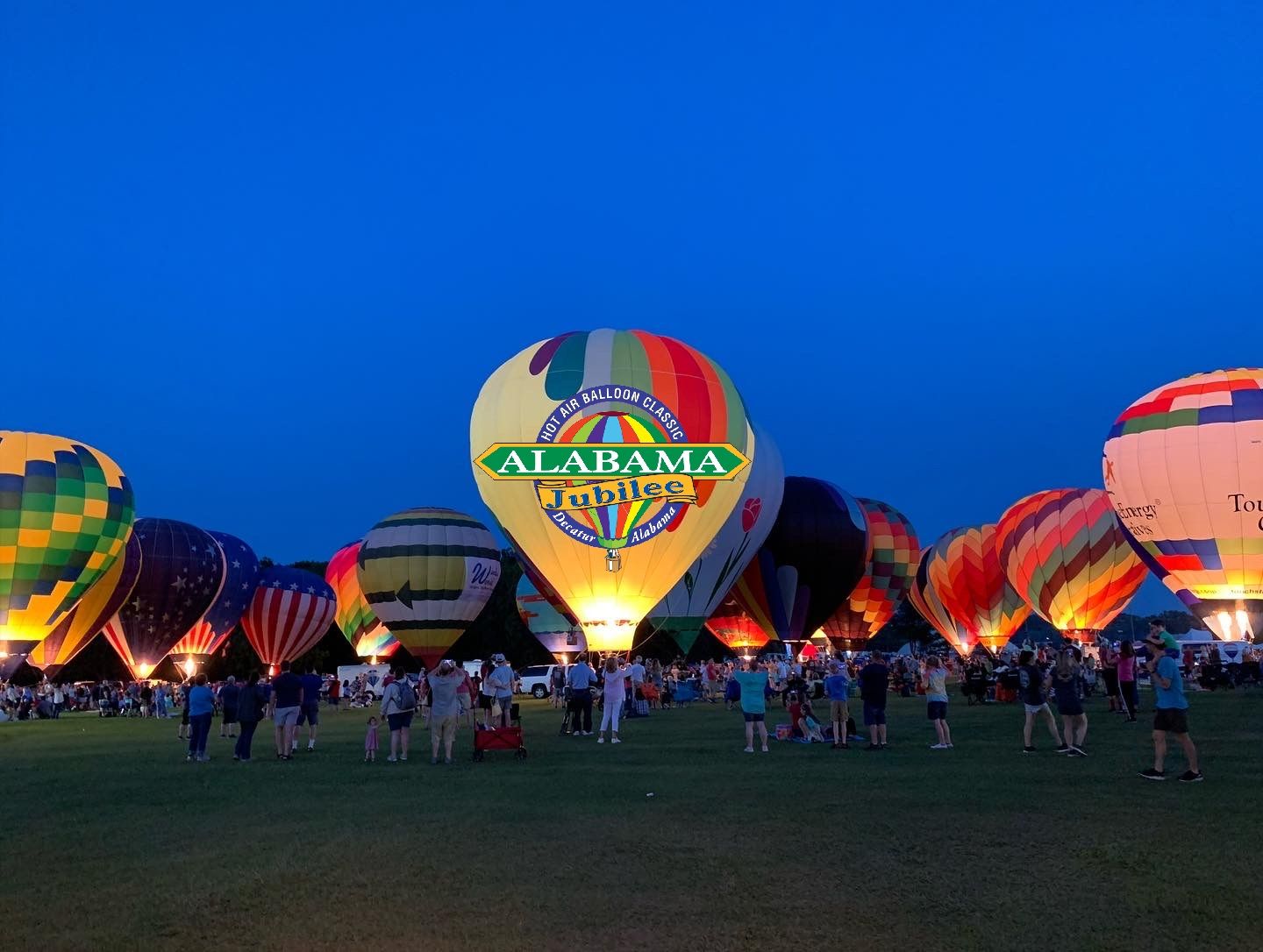 Hot air balloons glowing at dusk over a festival crowd in Decatur, Alabama
